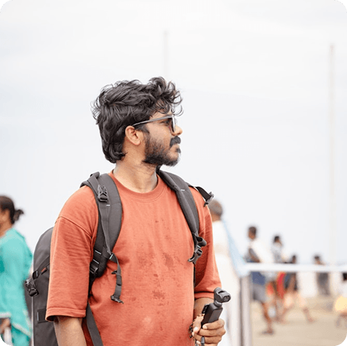 A traveler standing near the water with a phone